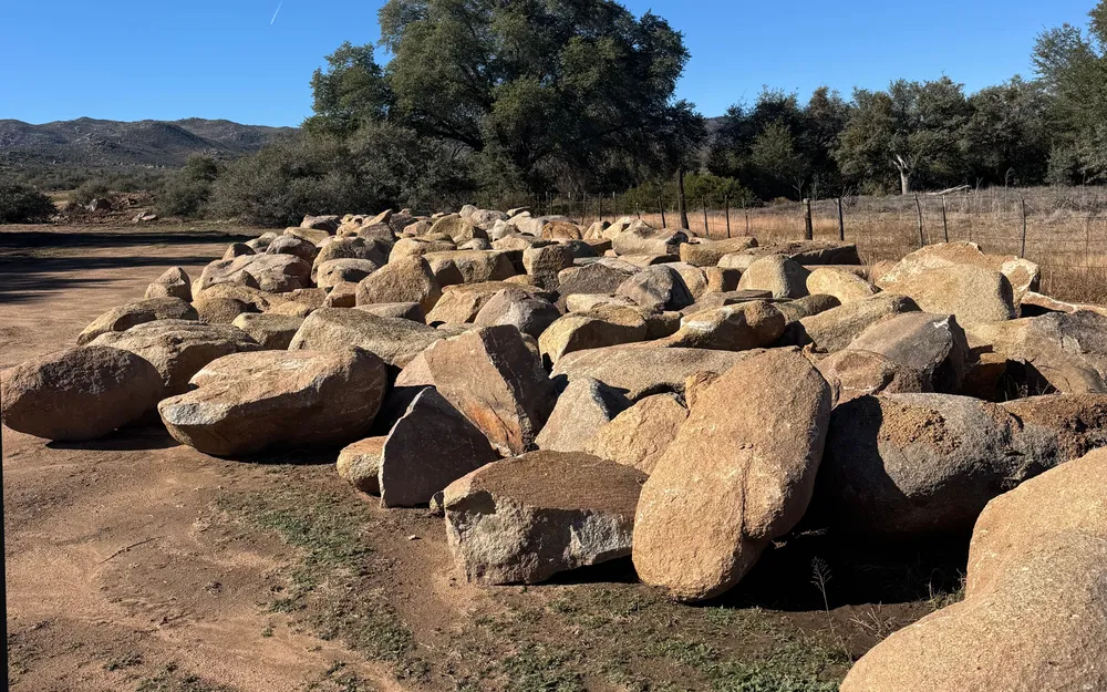 Row of salvaged granite boulders staged on a cleared lot near Prescott