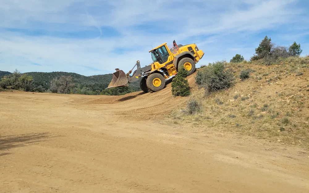Wheel loader grading down a slope under a dramatic sky near Prescott