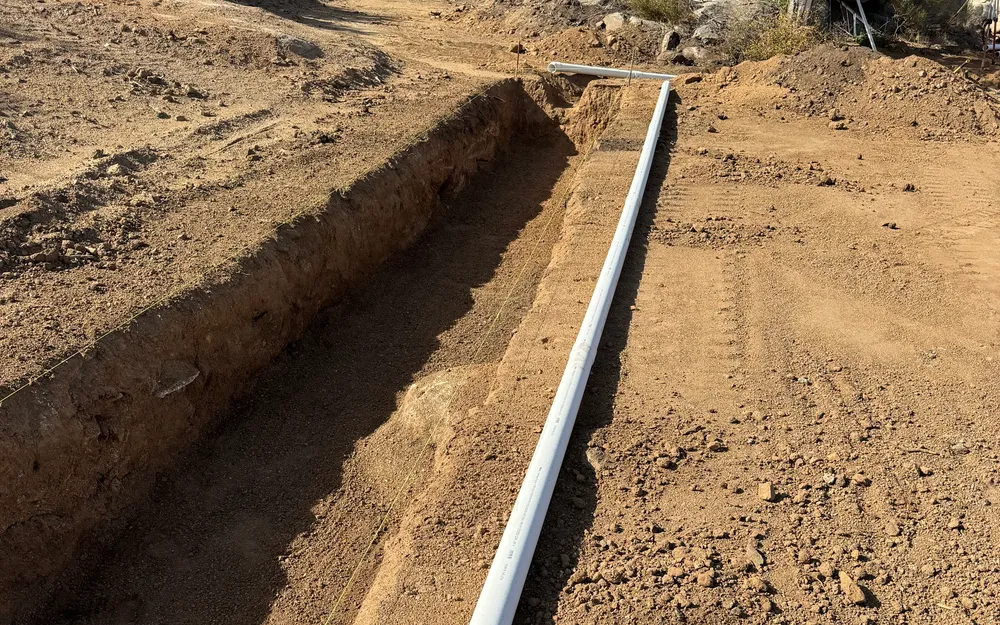Compact excavator digging a utility trench near Prescott